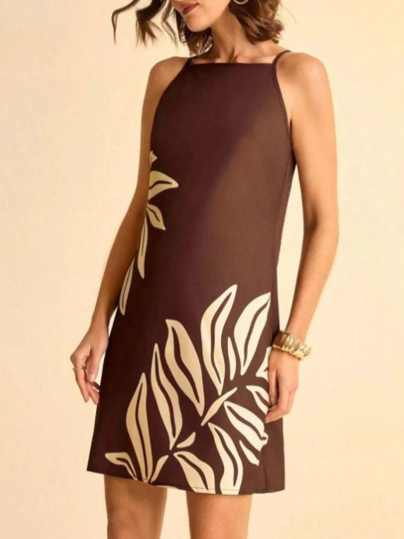 NEWYORKLISTED STYLE COLLECTION: Woman wearing a brown dress with white leaf patterns on a beige background