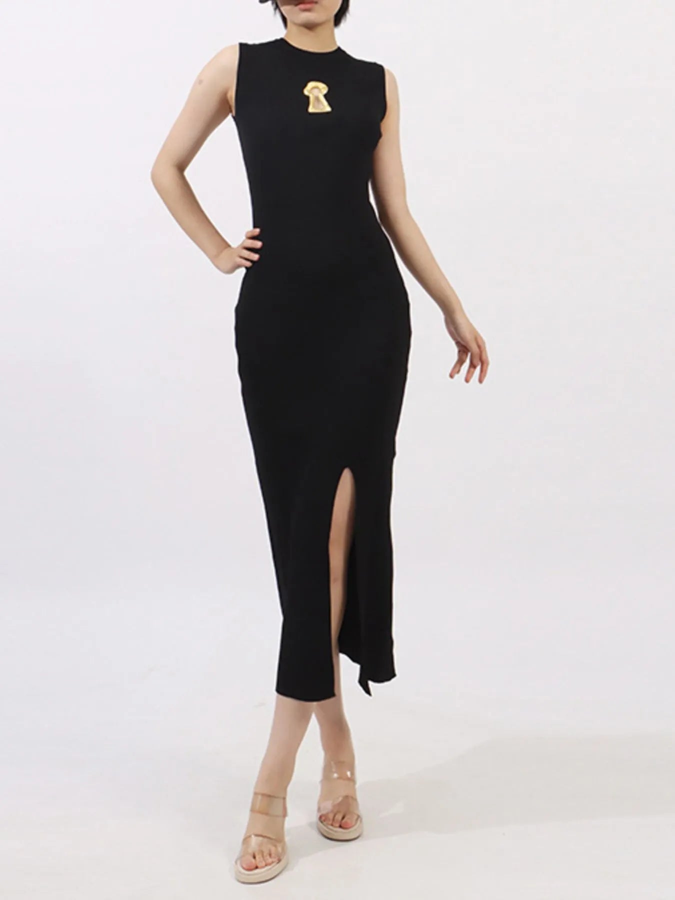 NEWYORKLISTED RUNWAY STYLE: Black sleeveless dress with a gold brooch on a white background