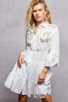 NEWYORKLISTED STYLE COLLECTION: Woman wearing a white embroidered dress against a gray background