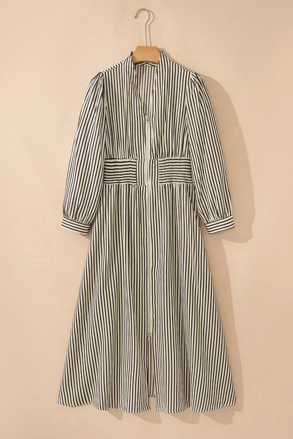NEWYORKLISTED STYLE COLLECTION: Striped dress on a hanger against a beige background