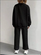 NEWYORKLISTED COMFORT COLLECTION: Person wearing a black textured sweater and pants set against a plain background