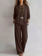 NEWYORKLISTED STYLE COLLECTION: A woman modeling a dark brown long-sleeve top and matching wide-leg pants set, accessorized with layered necklaces, bracelets, and sandals, against a neutral studio background.