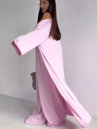 NEWYORKLISTED COMFORT COLLECTION: Woman wearing a long pink off-shoulder dress against a plain background