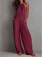 NEWYORKLISTED STYLE COLLECTION: Woman wearing a burgundy jumpsuit against a gray background