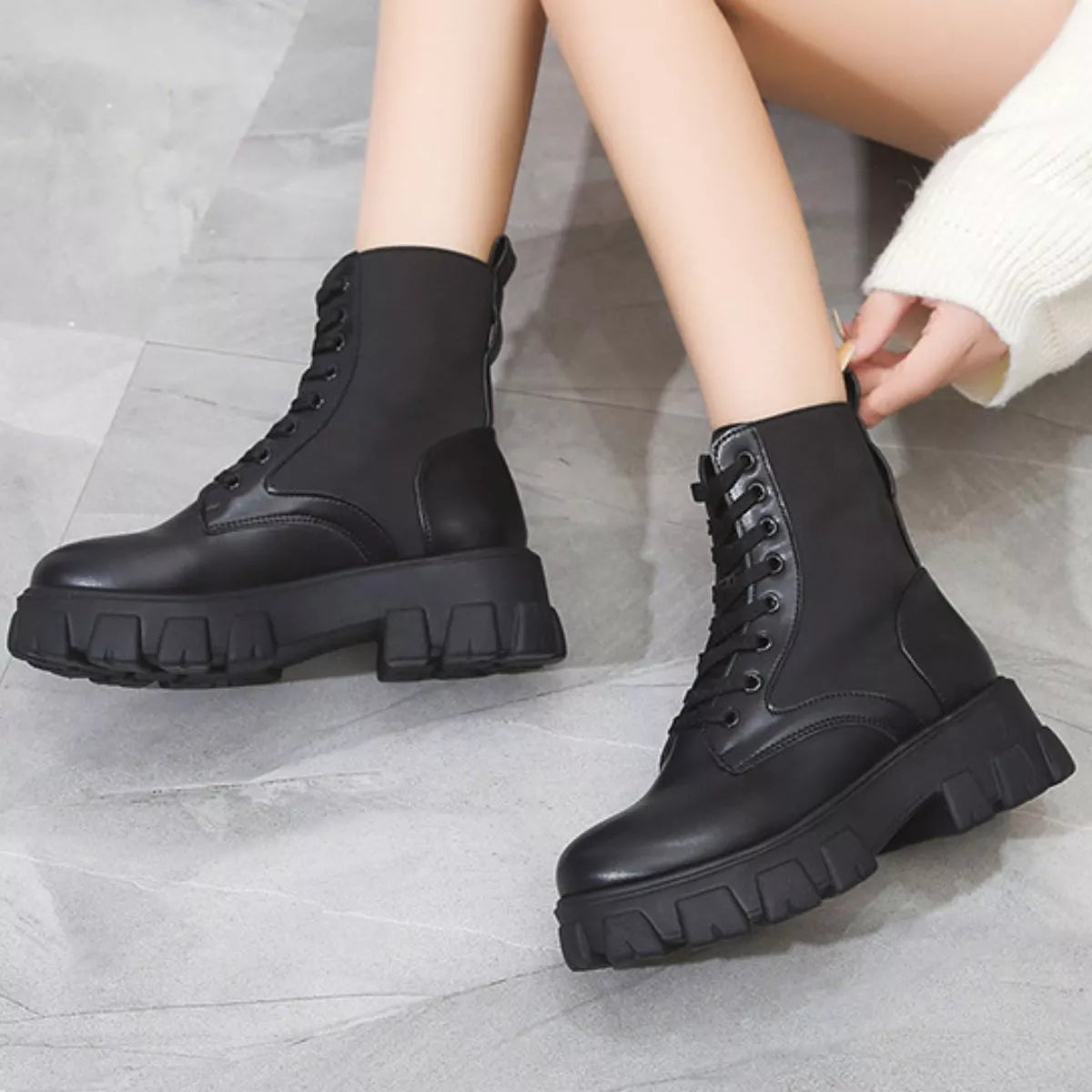 NEWYORKLISTED SHOE COLLECTION: Black combat boots worn by a person on a gray floor
