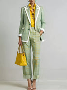 NEWYORKLISTED STYLE COLLECTION: A model wears a green and white checkered blazer and matching cropped trousers with white piping, styled with a yellow shirt, a yellow handbag, and yellow high-heeled sandals against a light gray studio background.
