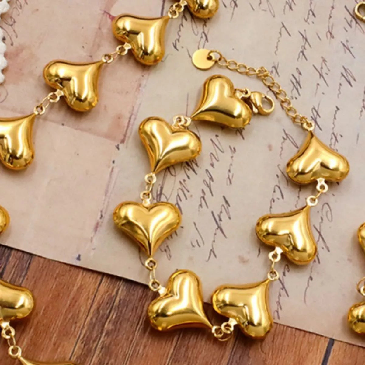 NYLD Glamour Collection by NEWYORKLISTED: Gold heart-shaped bracelet on a textured surface