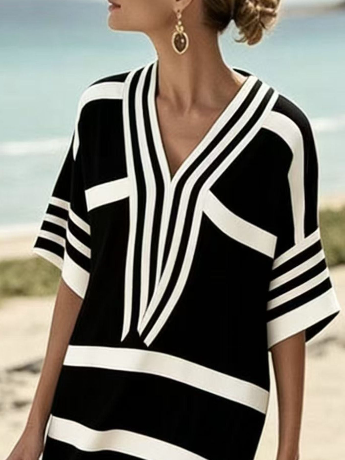 NEWYORKLISTED STYLE COLLECTION: Woman wearing a black and white striped cover-up on a beach.