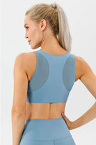 NEWYORKLISTED ACTIVEWEAR COLLECTION: Woman wearing a blue athletic top and leggings on a light gray background