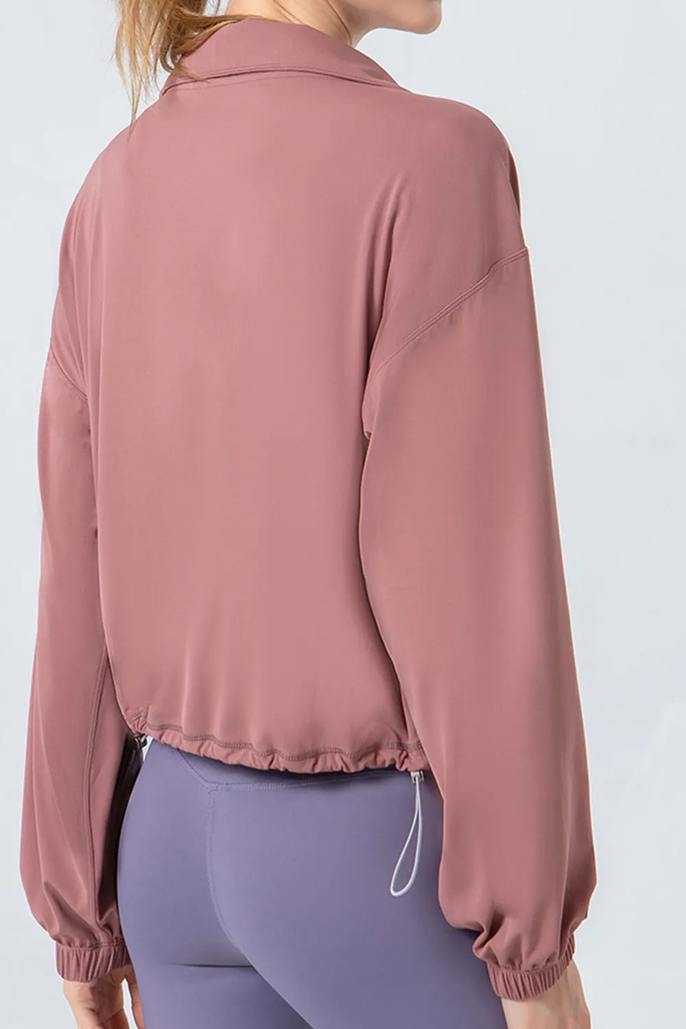 NEWYORKLISTED ACTIVEWEAR COLLECTION: Person wearing a pink jacket and purple leggings on a white background