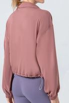 NEWYORKLISTED ACTIVEWEAR COLLECTION: Person wearing a pink jacket and purple leggings on a white background