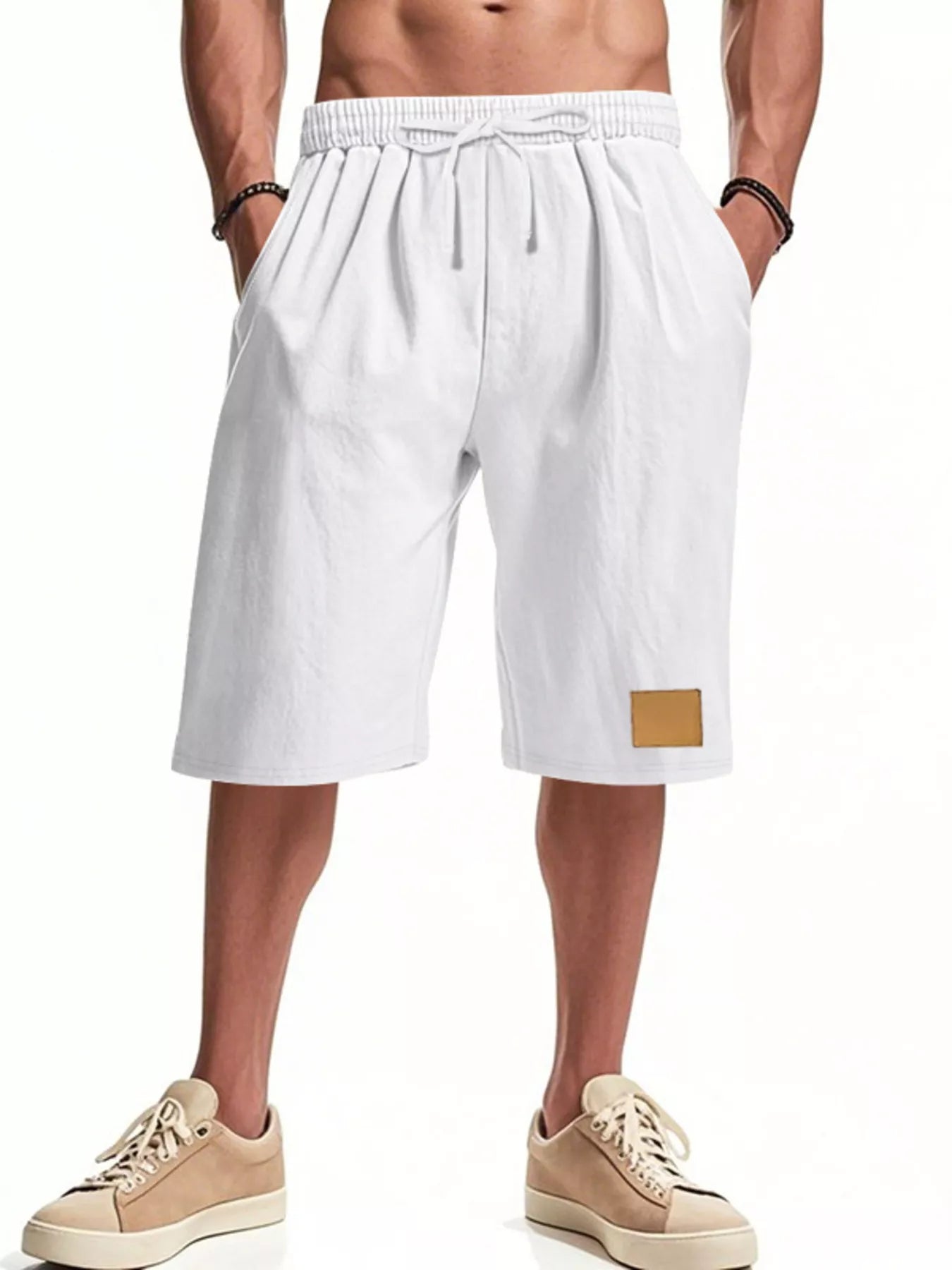NEWYORKLISTED ATLAS MEN'S COLLECTION: White shorts with a gold patch worn by a person on a white background