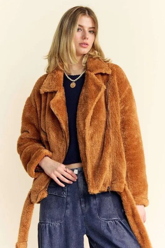 NEWYORKLISTED STYLE COLLECTION: Woman wearing a brown fuzzy jacket against a beige background