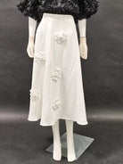 NEWYORKLISTED STYLE COLLECTION: Mannequin wearing a white dress with floral embellishments on a dark background