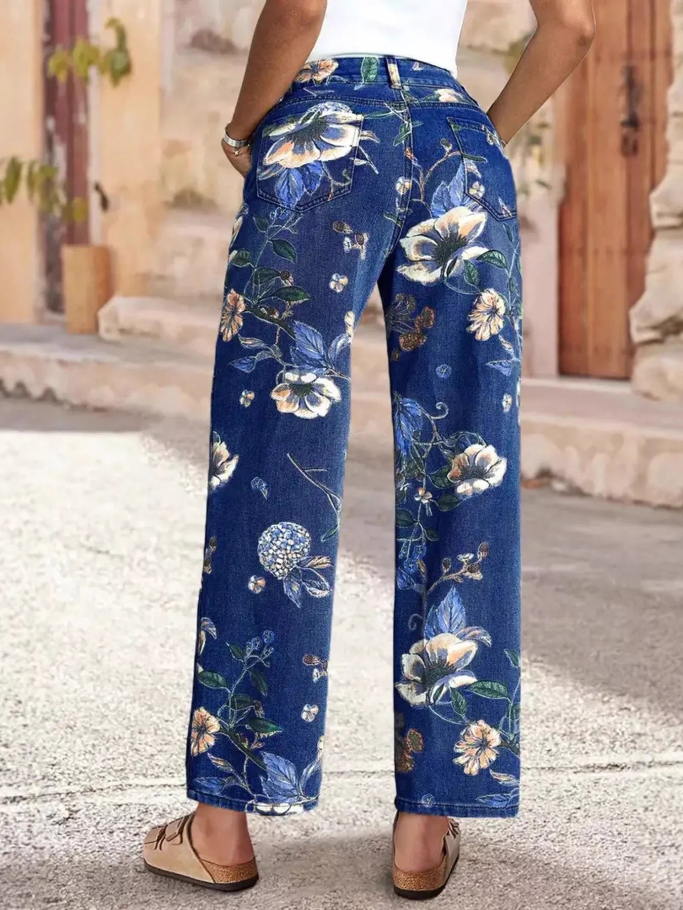 NEWYORKLISTED STYLE COLLECTION: Blue floral pants worn by a person on a stone pavement.