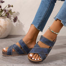 NEWYORKLISTED SHOE COLLECTION: Blue sandals worn with rolled-up jeans on a light wooden floor.