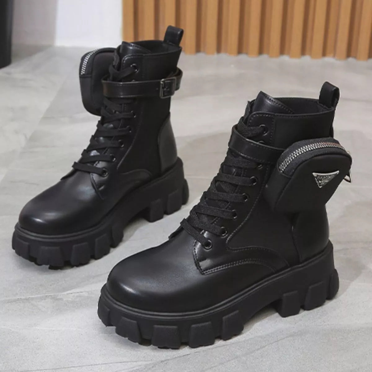 NEWYORKLISTED SHOE COLLECTION: Pair of black leather boots with chunky soles on a light gray surface.