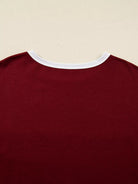 Close-up of a maroon shirt with white trim on a beige background