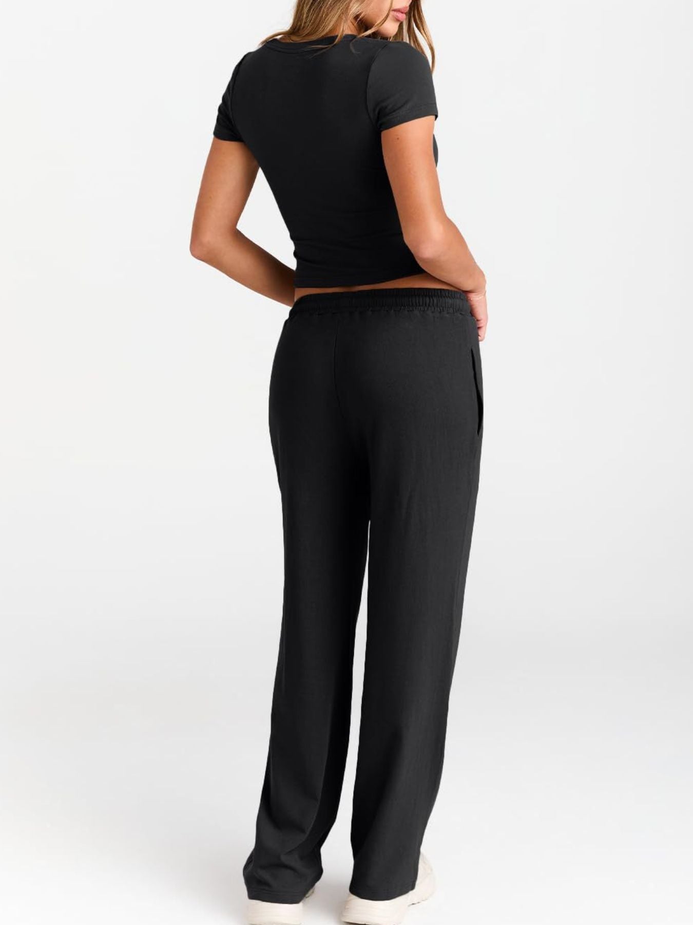 NEWYORKLISTED COMFORT COLLECTION: Person wearing a black outfit with wide-leg pants on a white background