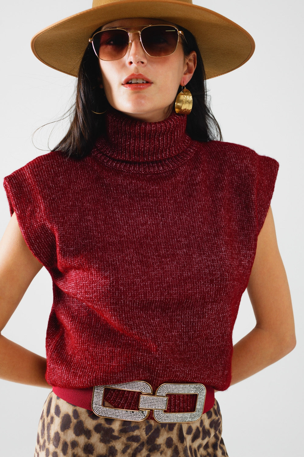 NEWYORKLISTED STYLE COLLECTION: Woman wearing a red sleeveless sweater, beige hat, and leopard print skirt against a white background