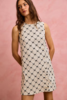 NEWYORKLISTED STYLE COLLECTION: Woman wearing a patterned dress against a pink background