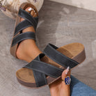 NEWYORKLISTED SHOW COLLECTION: Black sandals with brown soles worn by a person on a gray floor.