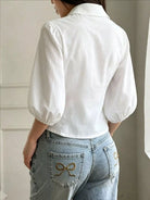 NEWYORKLISTED STYLE COLLECTION: A woman shown from the back wearing a white puff-sleeve collared blouse tucked into light-wash blue jeans with decorative bow embroidery on the back pockets.
