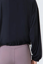 NEWYORKLISTED ACTIVEWEAR COLLECTION: Black long-sleeve top worn by a person on a white background