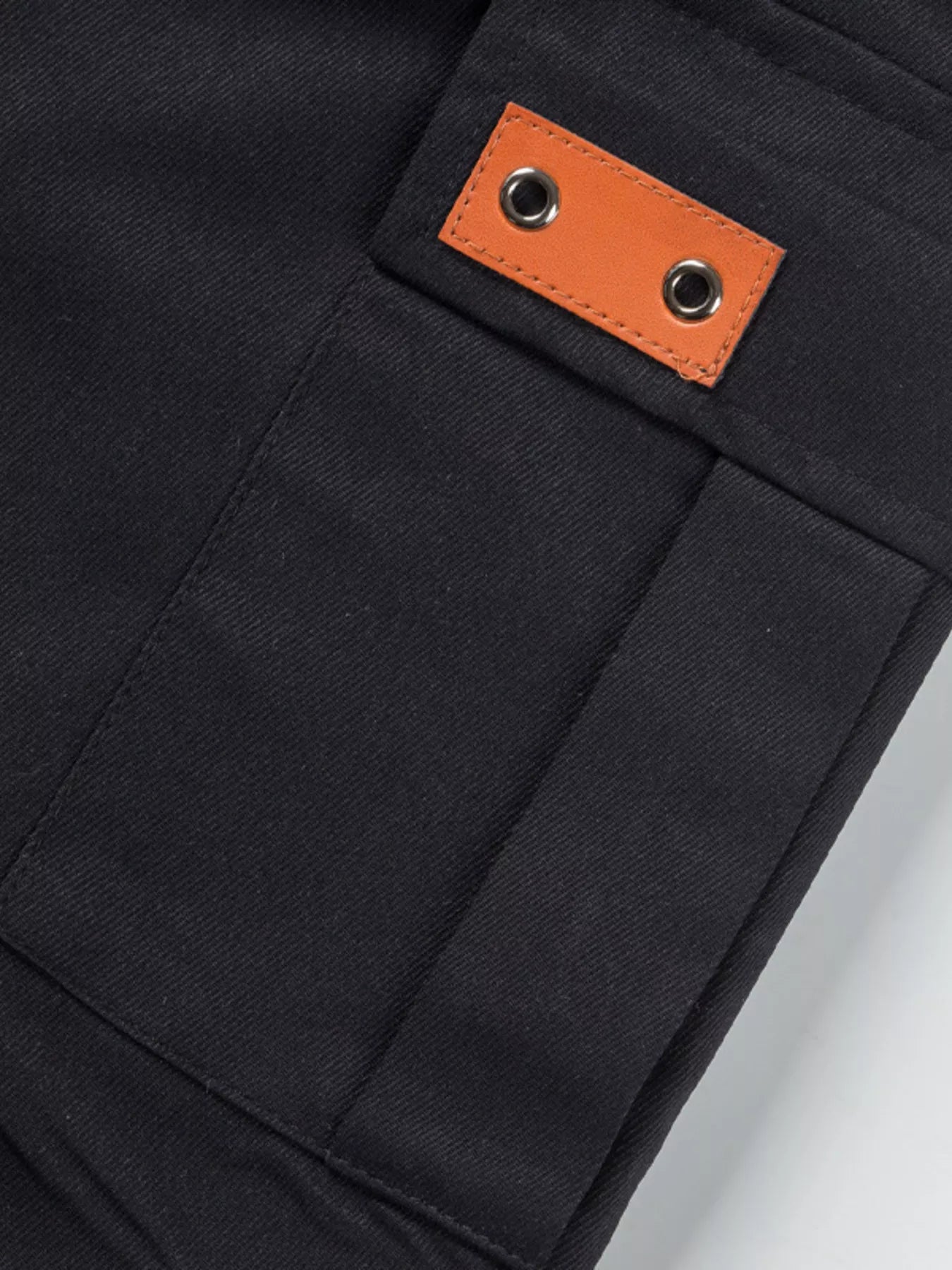 NEWYORKLISTED ATLAS MEN'S COLLECTION: Close-up of a black pocket with an orange leather patch on a white background