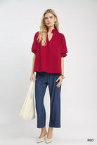 NEWYORKLISTED Style Collection: Woman wearing a red blouse and blue pants holding a white bag on a white background