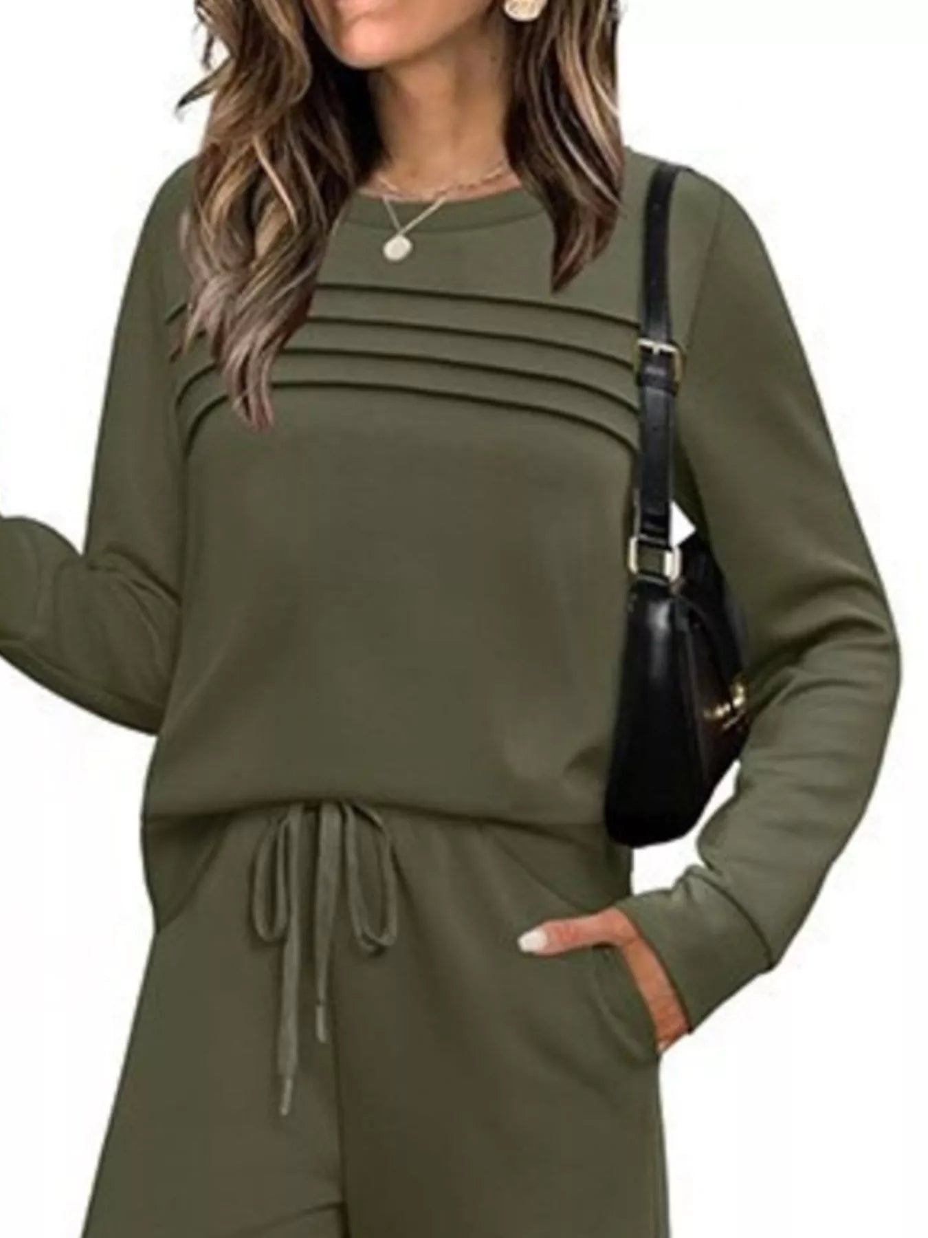 NEWYORKLISTED COMFORT COLLECTION: Woman wearing an olive green outfit with a black handbag on a white background