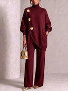 NEWYORKLISTED STYLE COLLECTION: A model wears a matching burgundy knit turtleneck sweater and wide-leg trousers set with large gold-tone decorative buttons. She is holding a small metallic gold handbag and wearing gold pointed shoes, set against a neutral textured studio backdrop.