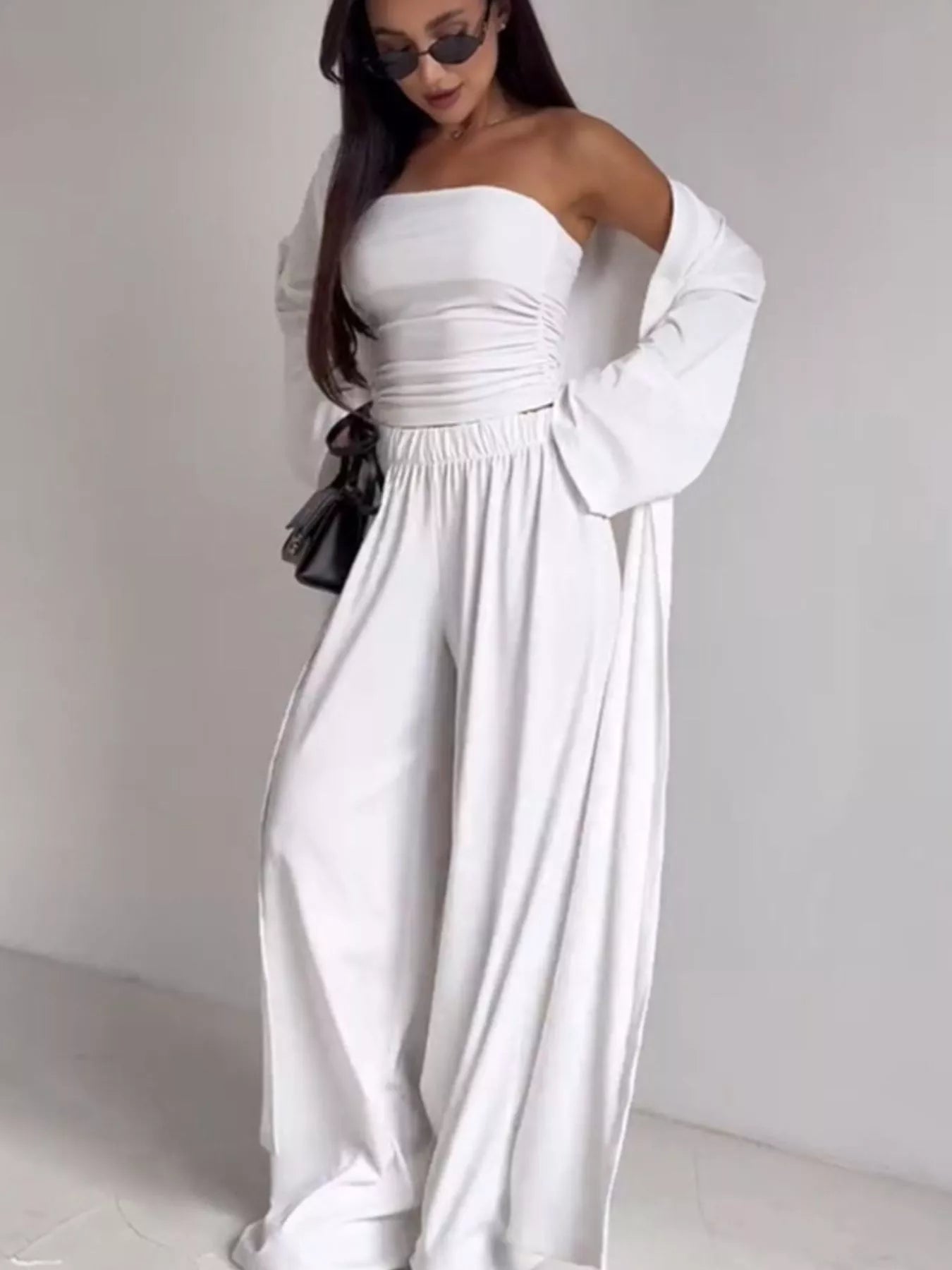 NEWYORKLISTED COMFORT COLLECTION: Woman wearing a white off-shoulder dress with long sleeves on a plain background