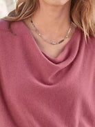 NEWYORKLISTED STYLE COLLECTION: Close-up of a person wearing a pink garment and a necklace with a blurred background