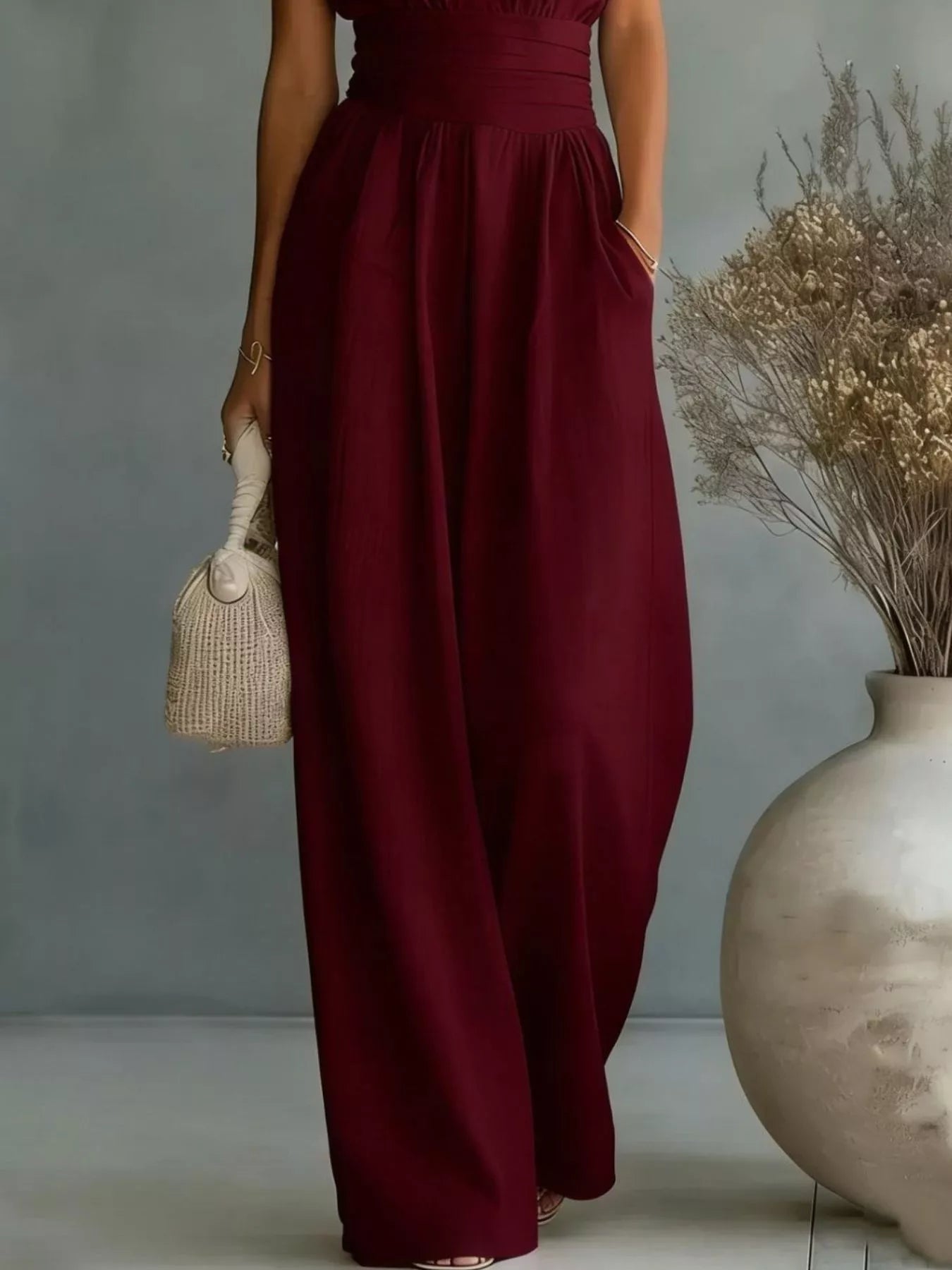 NEWYORKLISTED STYLE COLLECTION: Person wearing a burgundy dress holding a small bag against a neutral background