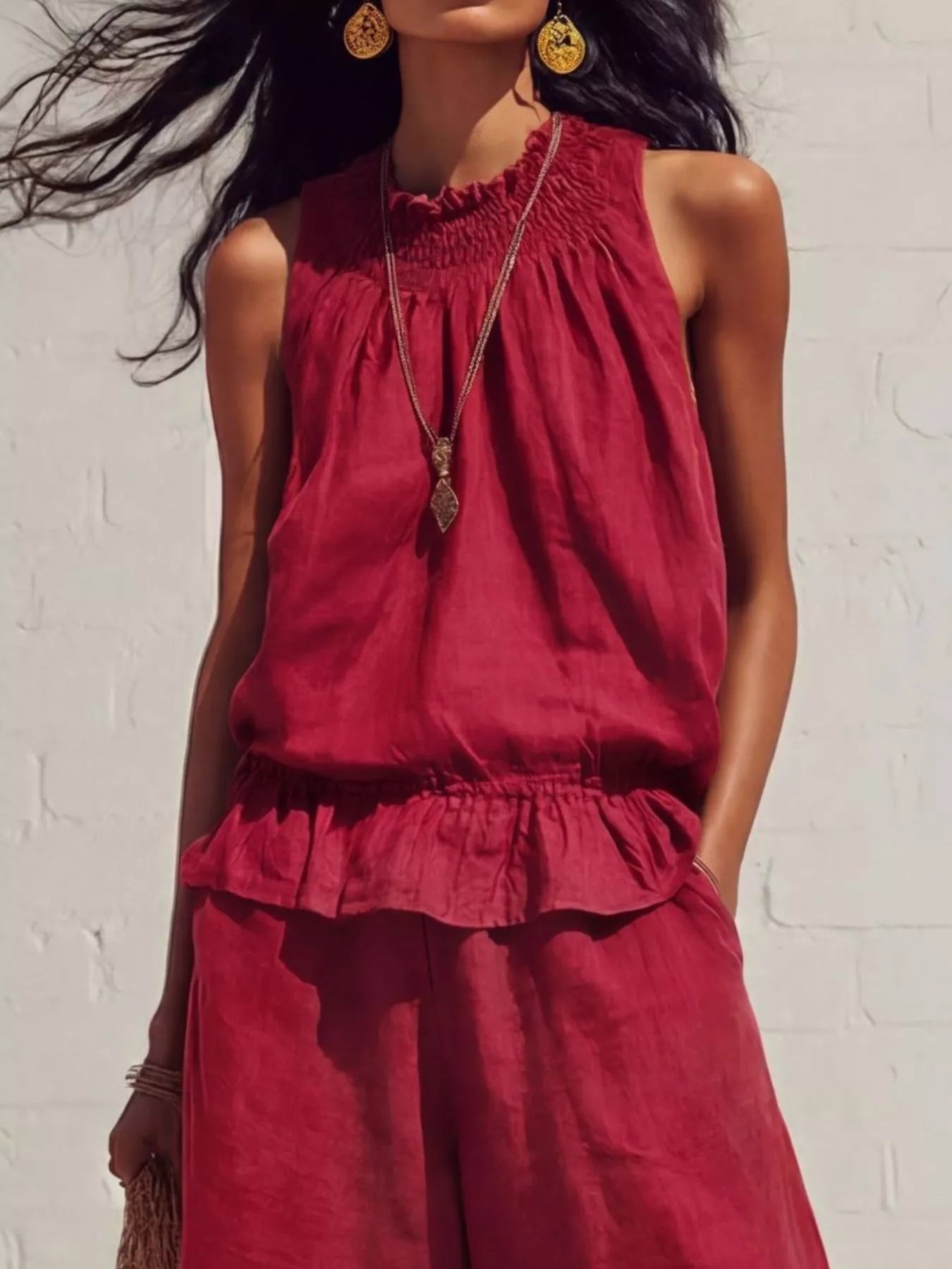 NEWYORKLISTED STYLE COLLECTION: Woman wearing a red sleeveless top and pants against a white brick wall.