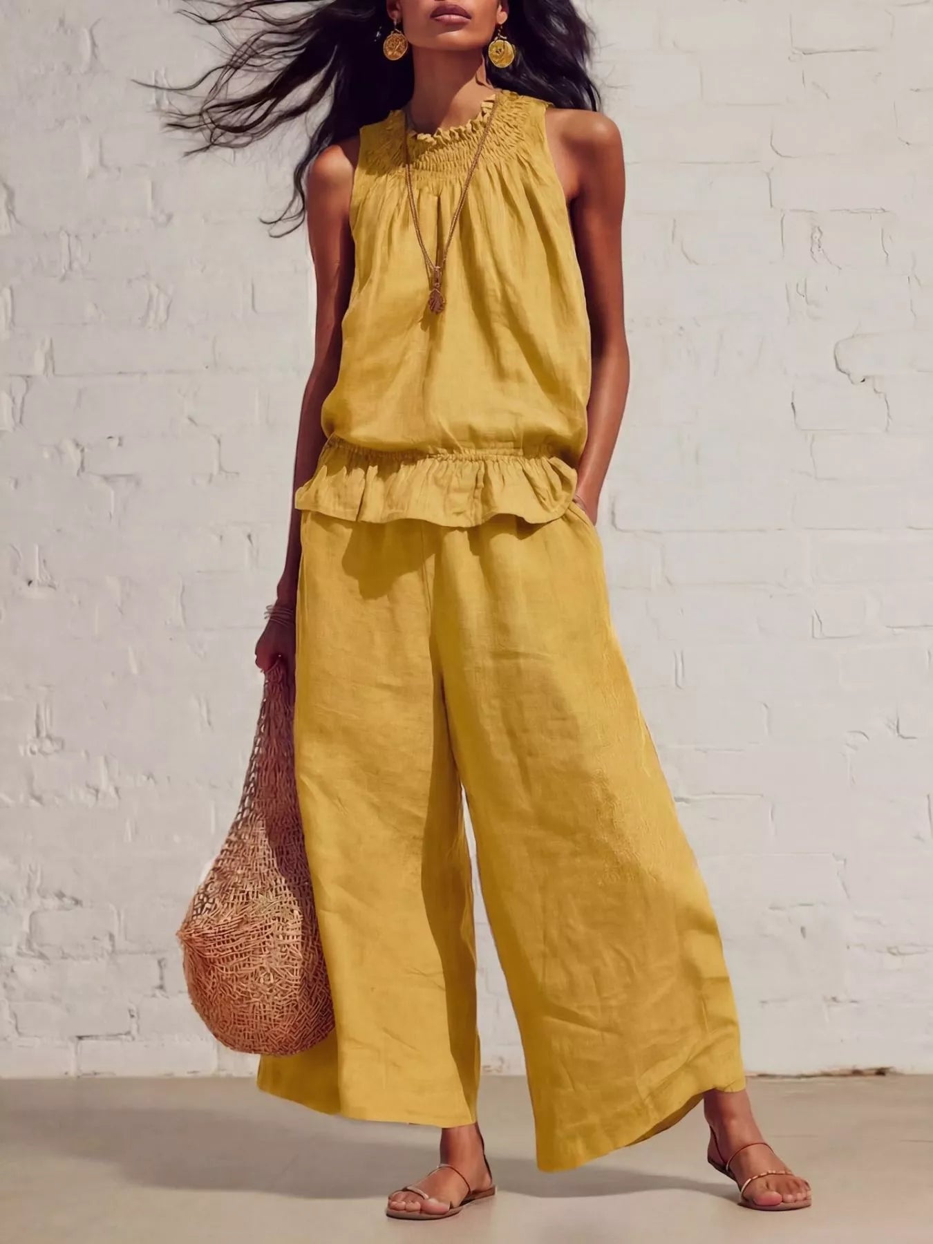 NEWYORKLISTED STYLE COLLECTION: Woman wearing a yellow outfit with wide-leg pants against a white brick wall.