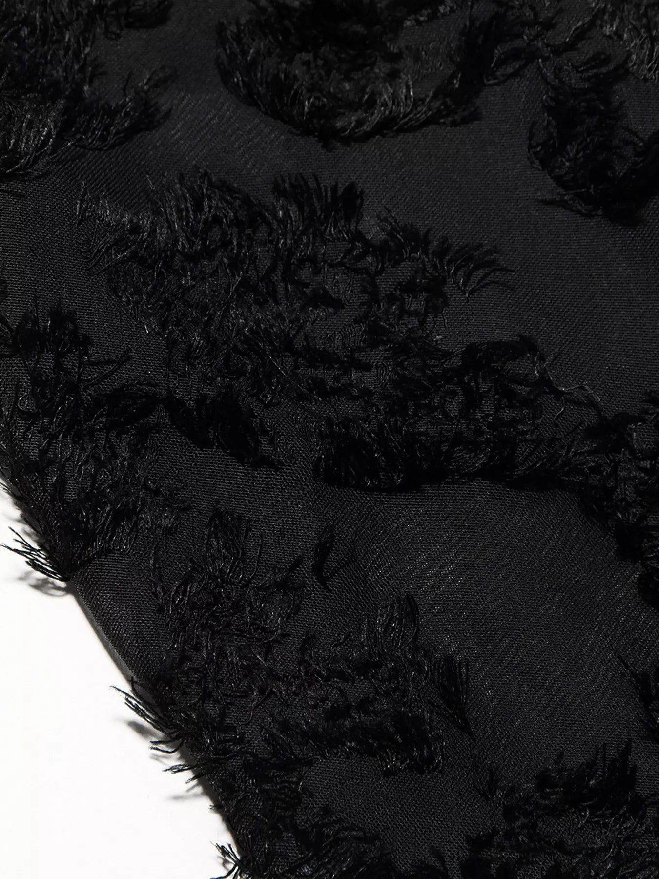 NEWYORKLISTED STYLE COLLECTION: Close-up of black textured fabric with frayed edges on a dark background