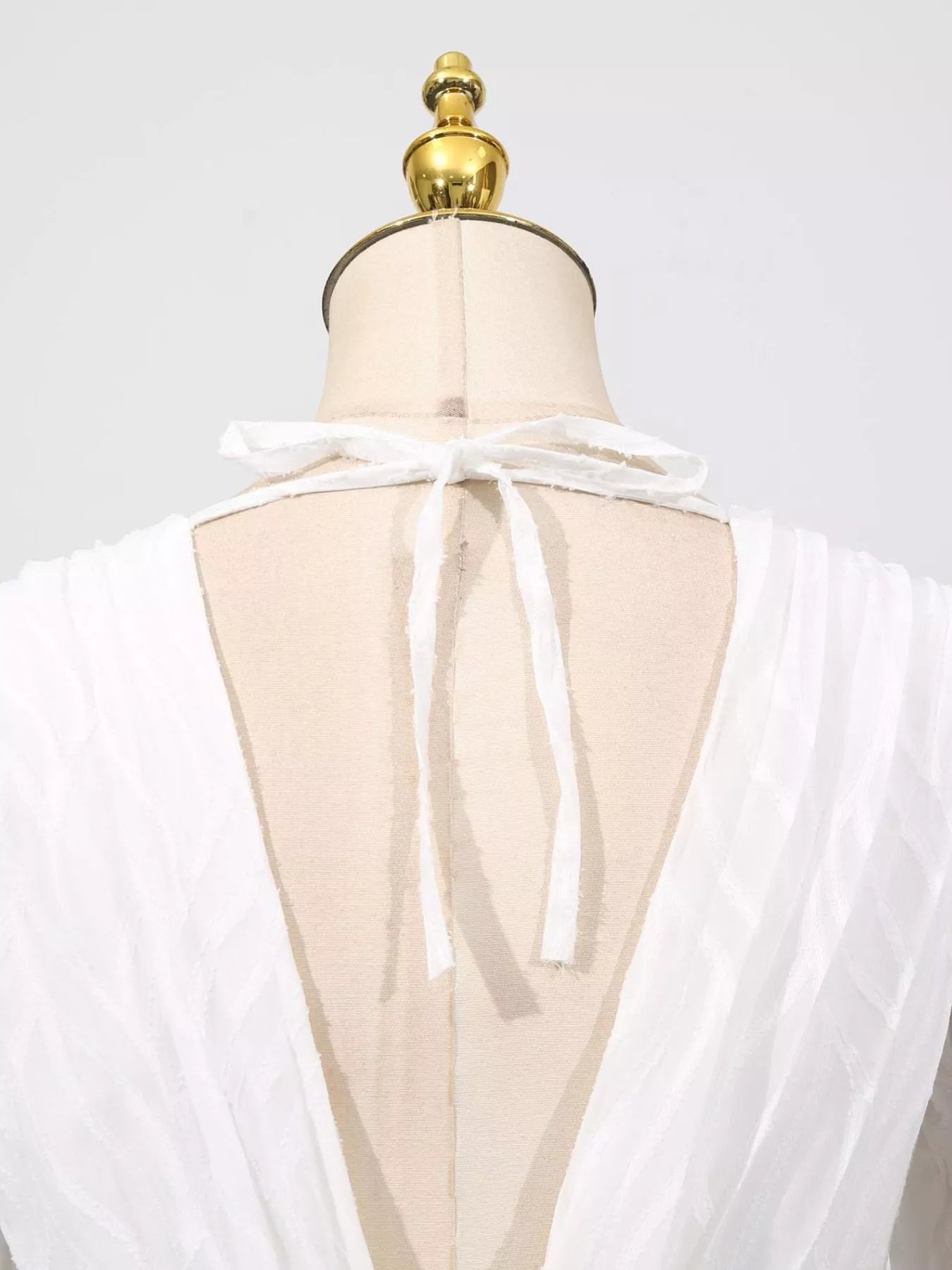 NEWYORKLISTED STYLE COLLECTION: White sheer top on a mannequin with a gold top against a white background