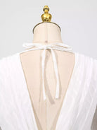 NEWYORKLISTED STYLE COLLECTION: White sheer top on a mannequin with a gold top against a white background