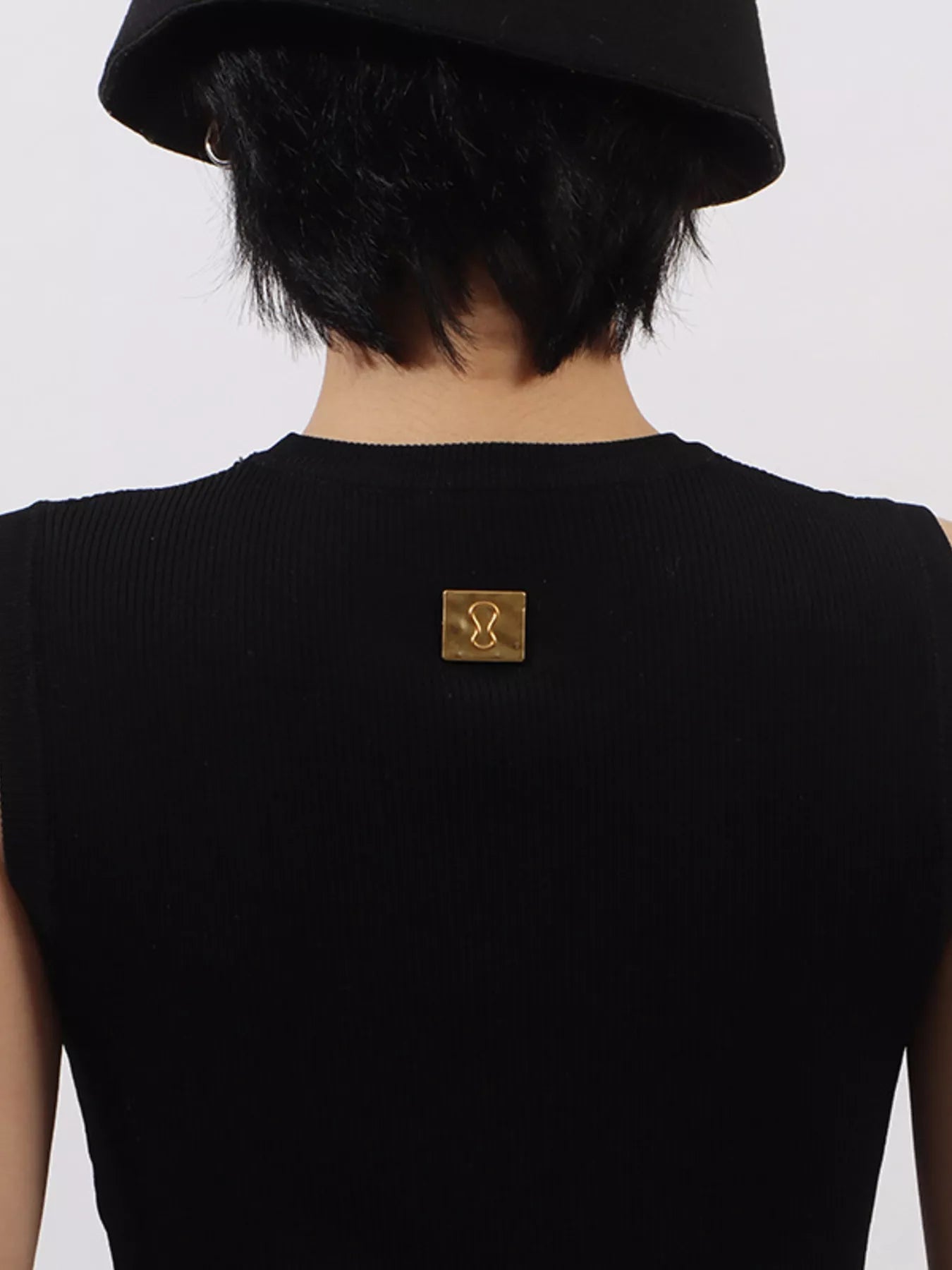 Person wearing a black top with a gold logo on a white background