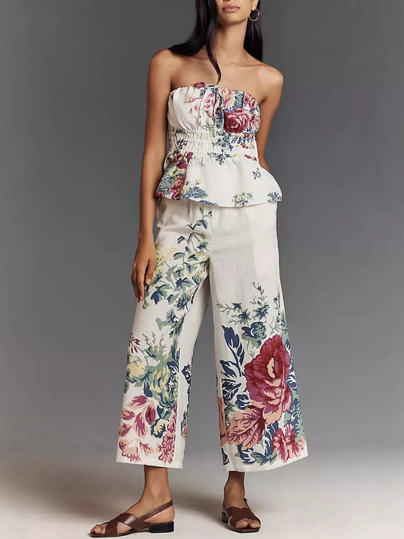 NEWYORKLISTED STYLE COLLECTION: Woman wearing a floral strapless top and wide-leg pants against a gray background