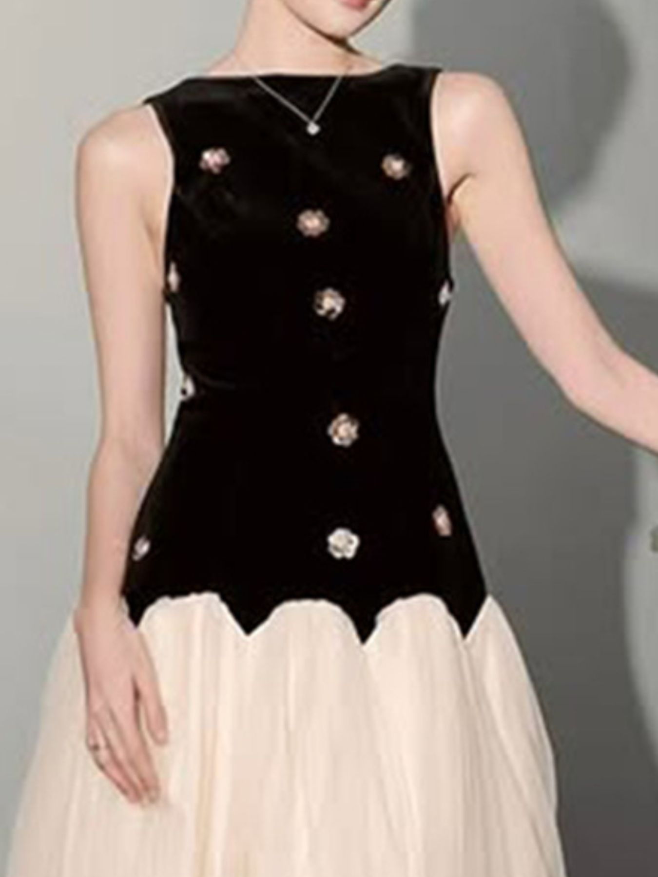 NEWYORKLISTED STYLE COLLECTION: Black sleeveless top with decorative buttons worn by a person on a gray background