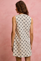NEWYORKLISTED STYLE COLLECTION: Woman wearing a sleeveless dress with a geometric pattern against a pink background