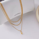 NYLD Glamour Collection by NEWYORKLISTED: Gold chain necklace with a small pendant on a white surface with 'GENTLE MONSTER' branding.