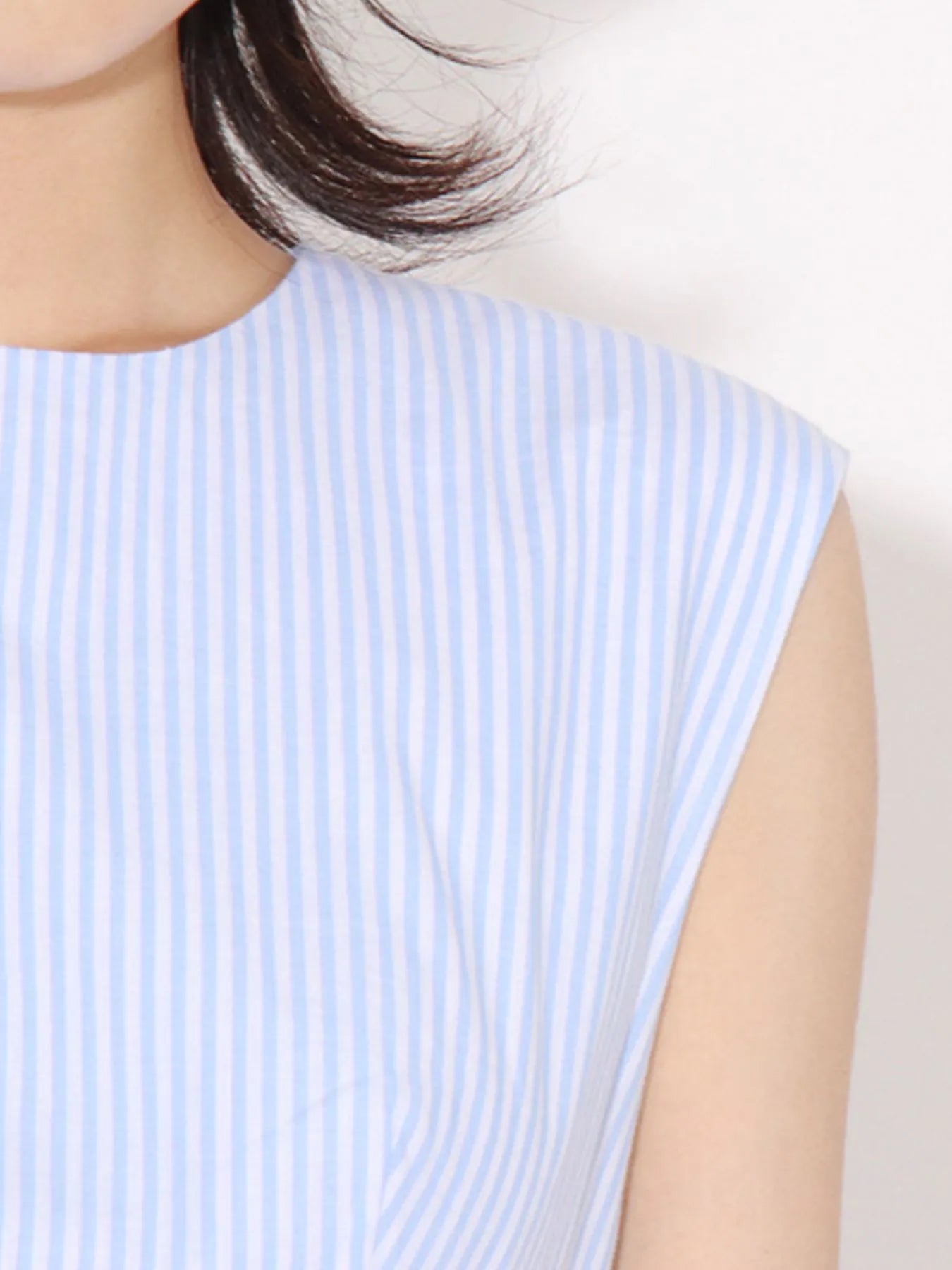 NEWYORKLISTED RUNWAY STYLE: Light blue and white striped sleeveless top worn by a person on a plain background