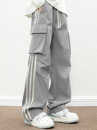 NEWYORKLISTED ATLAS MEN's COLLECTION: Person wearing gray pants with white stripes and white sneakers on a plain background